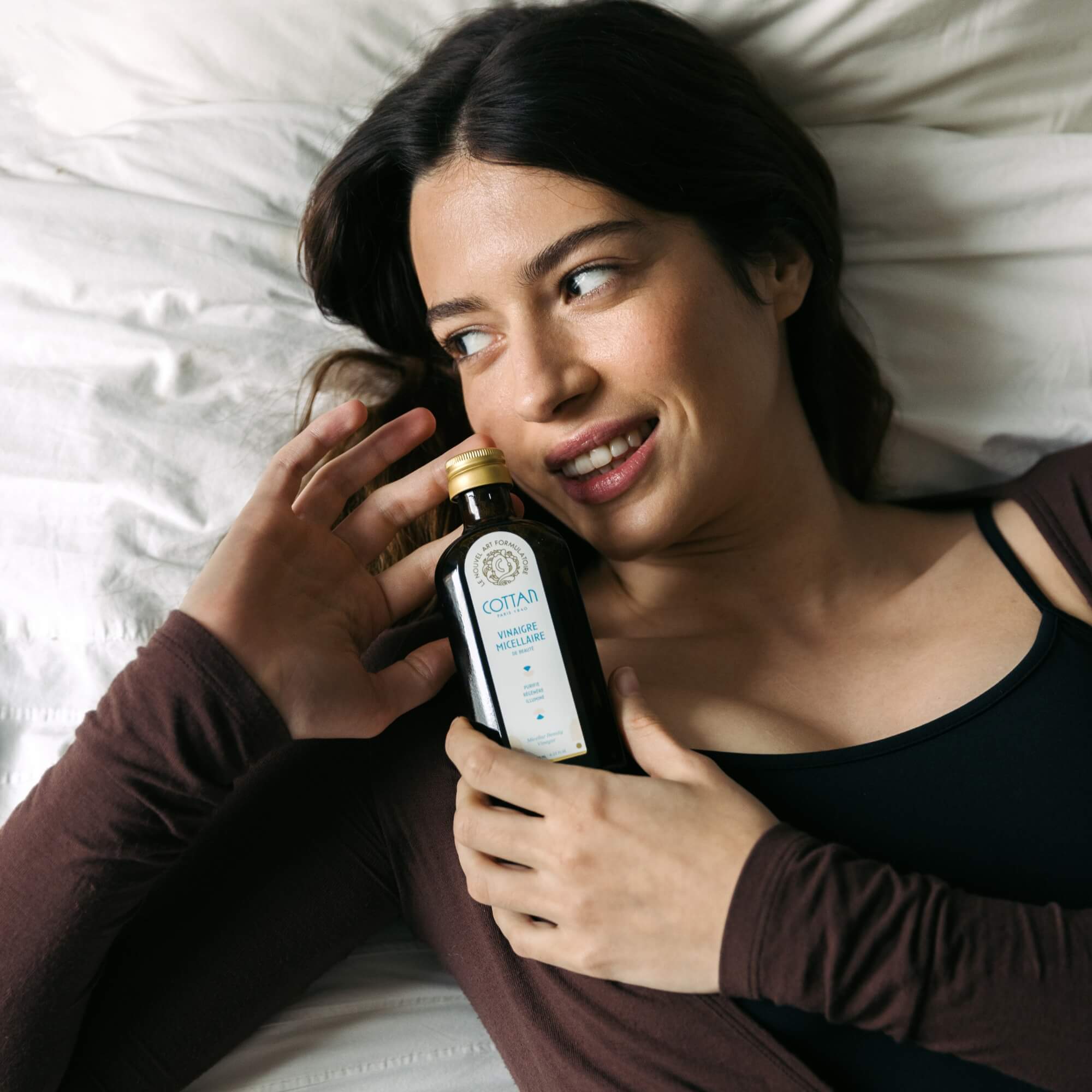 Scène lifestyle mettant en scène l’utilisation du Vinaigre Micellaire de Beauté COTTAN Paris 1840 dans un moment de détente. Le geste doux et spontané, la proximité avec la peau et l’atmosphère intime illustrent un rituel de nettoyage sensoriel, révélant une peau fraîche, lumineuse et naturellement équilibrée.