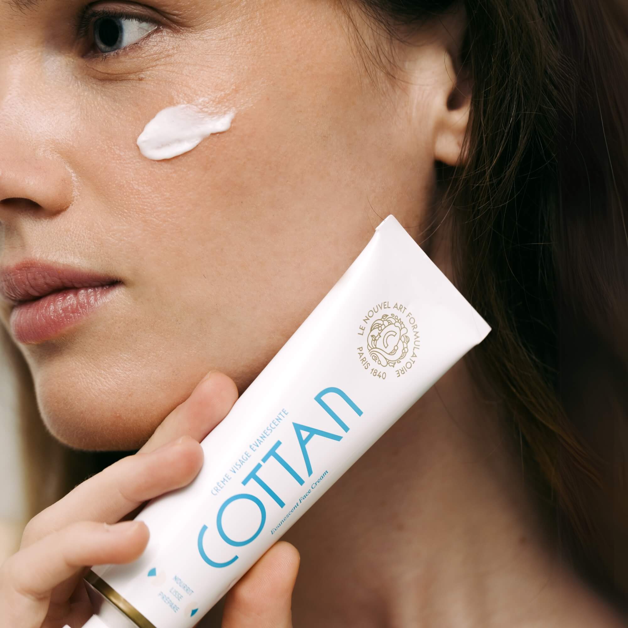 Gros plan d’une application de la Crème Visage Évanescente sur la joue, illustrant la texture fine et fondante du soin. Image lifestyle soulignant la sensorialité, la légèreté de la crème et l’éclat naturel de la peau.